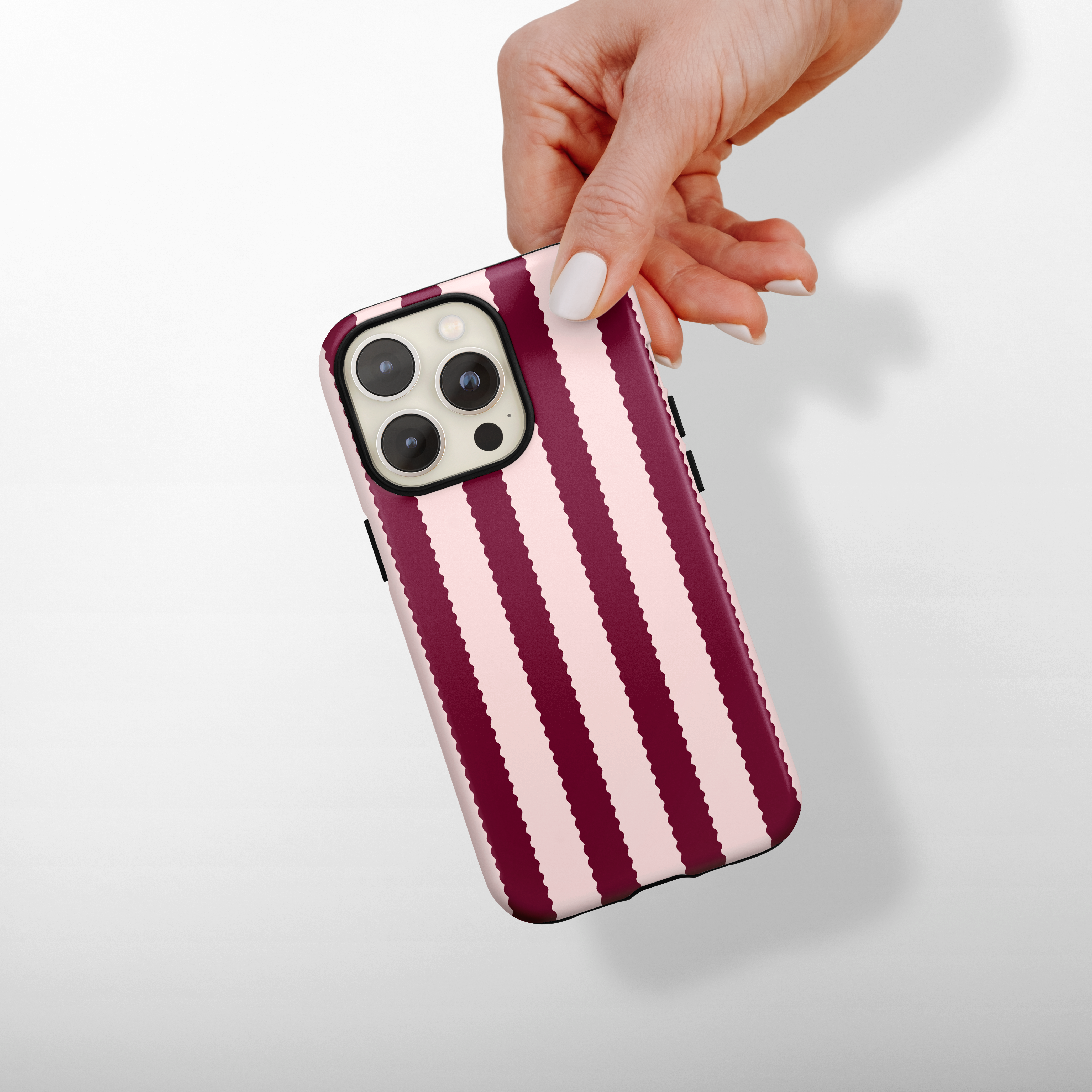 Hand holding a Coconut Lane tough phone case with blushberry scallop stripes pattern on a white background.