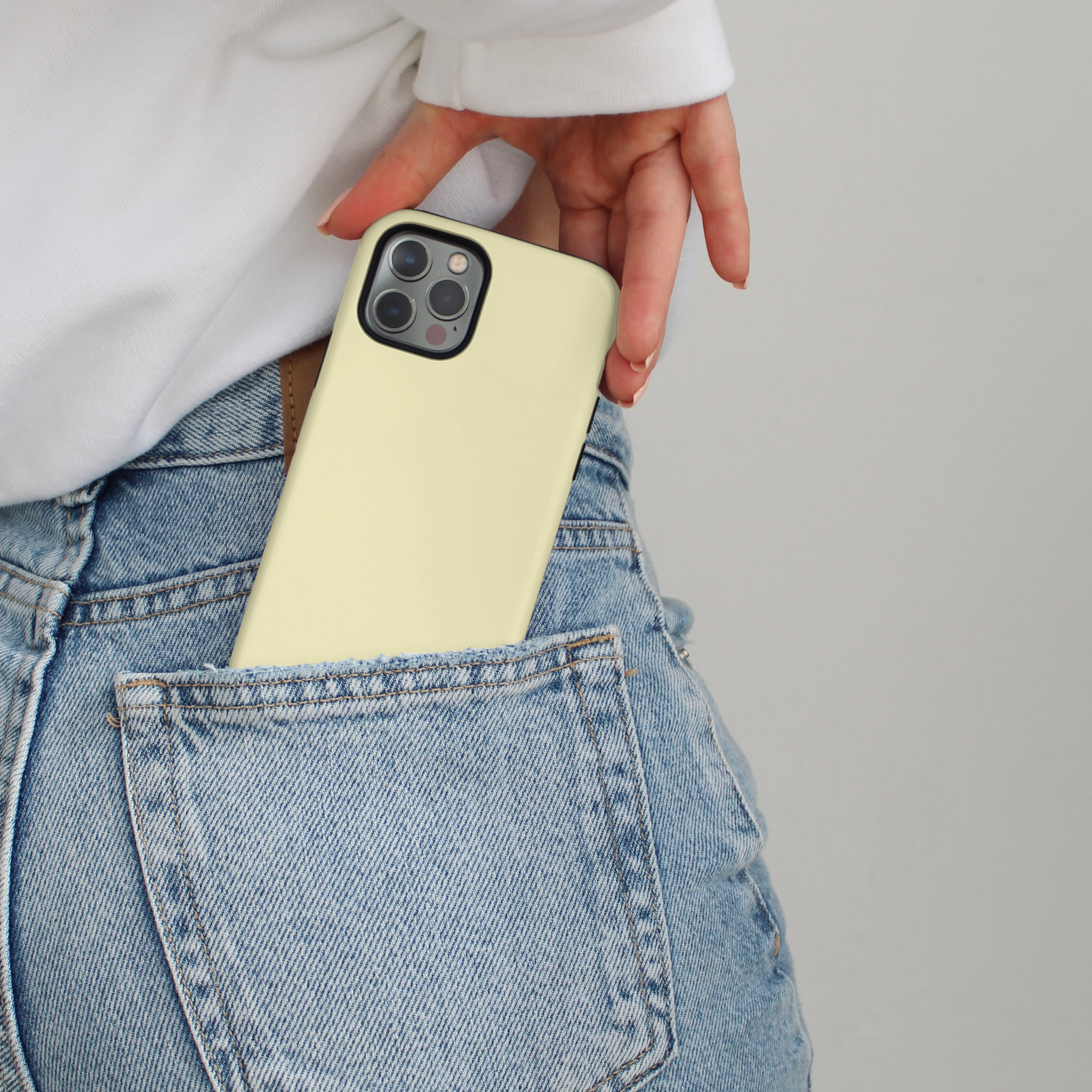 Yellow Coconut Lane Tough MagSafe® phone case being slid into the back pocket of light blue jeans.