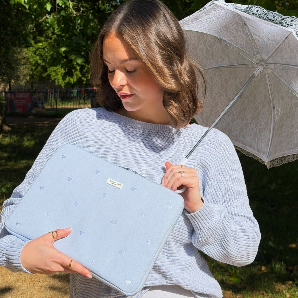 Woman holding powder blue hearts laptop sleeve a white lace umbrella