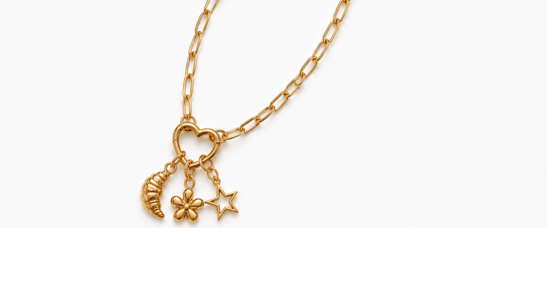 A gold chain necklace with a heart pendant, crescent moon, flower, and star charms. "THE CHARM STUDIO" text appears in black in the lower right corner on a white background.