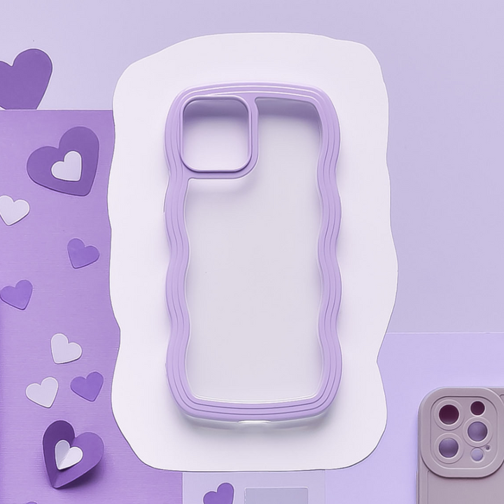 A Coconut Lane Curvy Phone Case - Lilac with a wavy edge design is placed on a white abstract cutout against a purple background. Decorated with paper hearts in various shades of purple, the scene also shows another phone and Highly Protective phone case with a different design in the background.