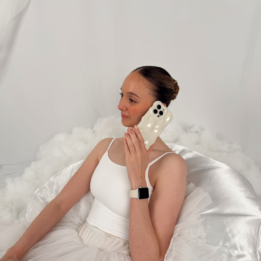 Girl on phone sat in a cloud chair with the 3D Bubble Phone Case in Cloud Dancer