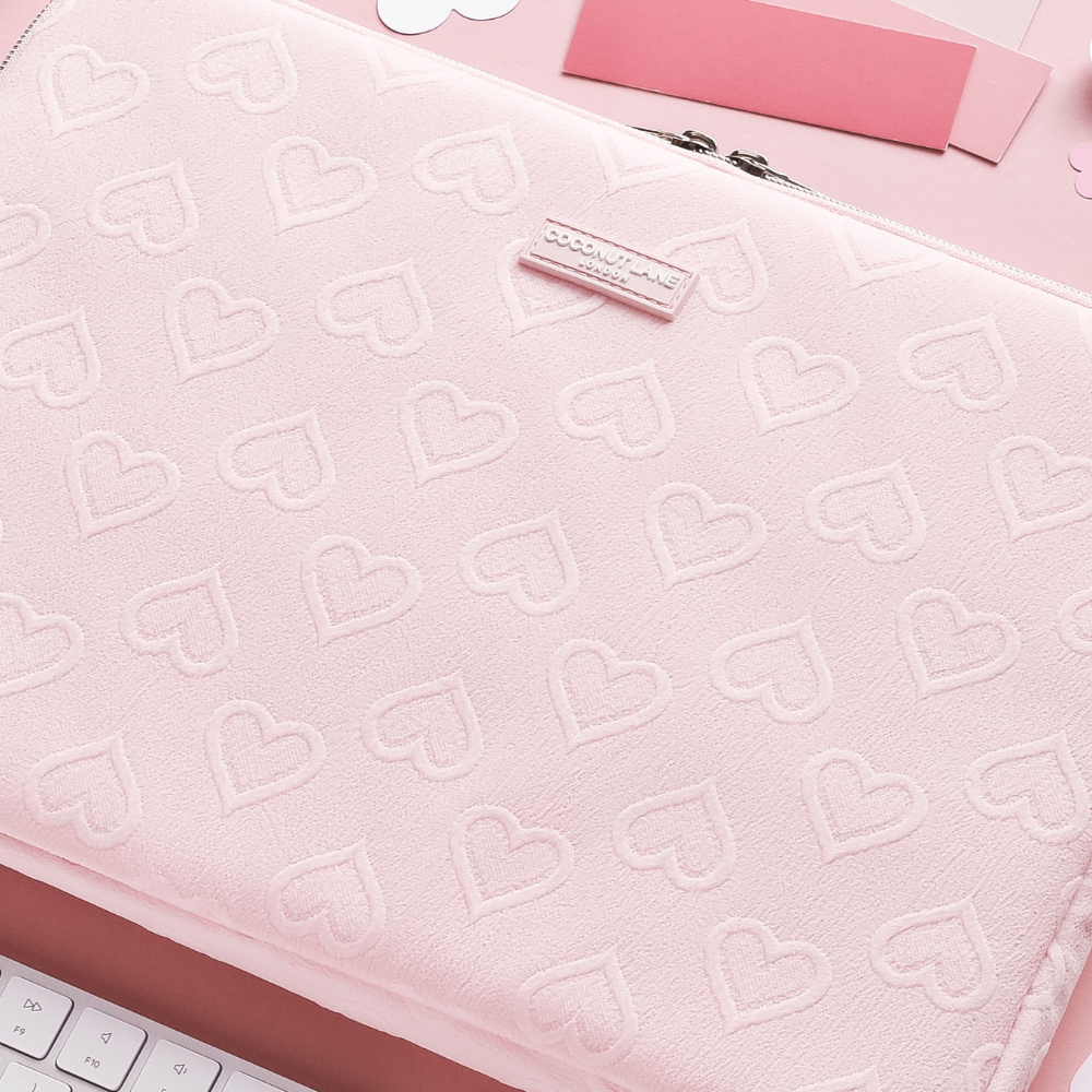 Pastel pink laptop sleeve with embossed heart pattern and smooth finish.