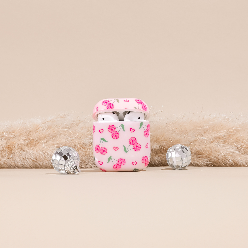 Coconut Lane Disco Cherries AirPods case with wireless earbuds, cherry pattern, and disco balls on beige background.
