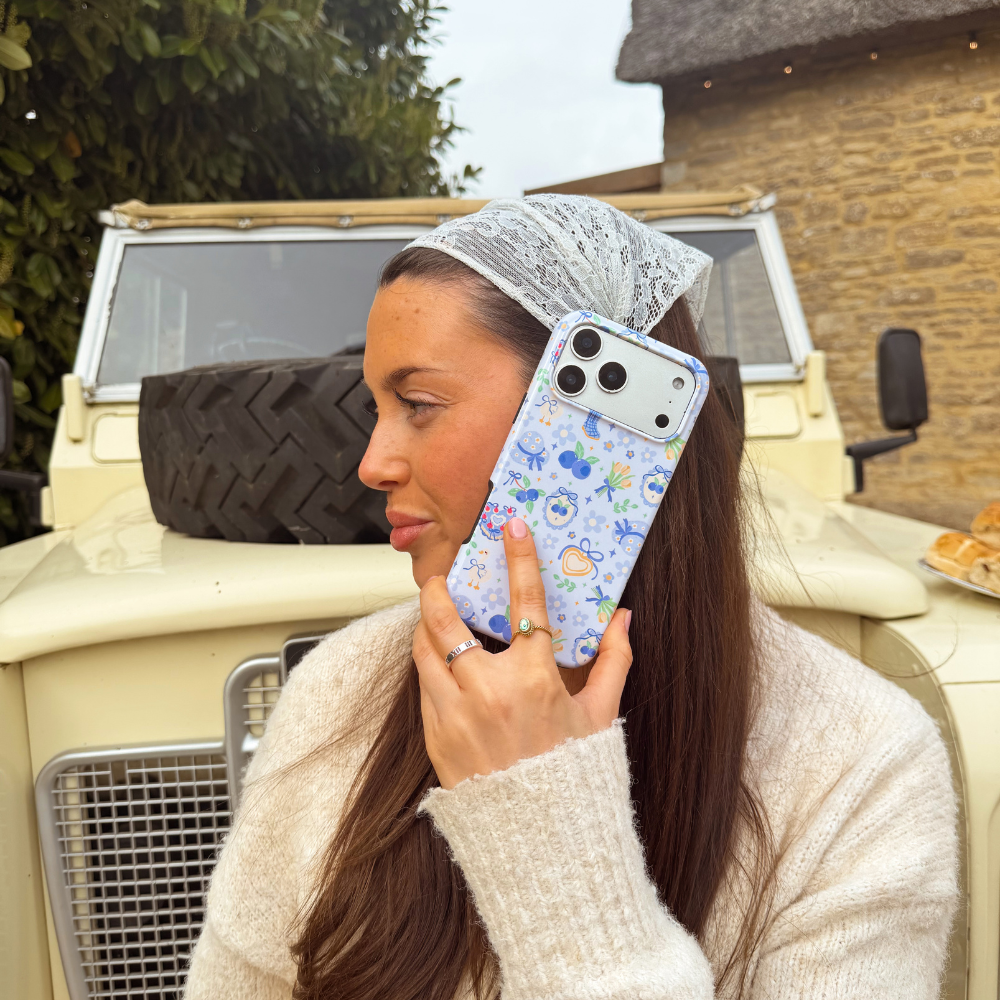 Girl holding blueberry picnic phone case to ear 