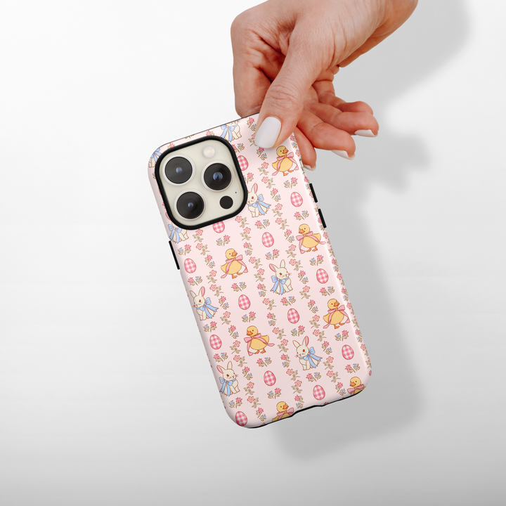 Phone case with bunnies and chick pattern held by a hand on a light background