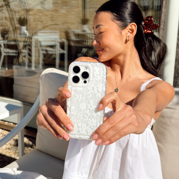 girl taking selfie wearing white to match her white lace phone case