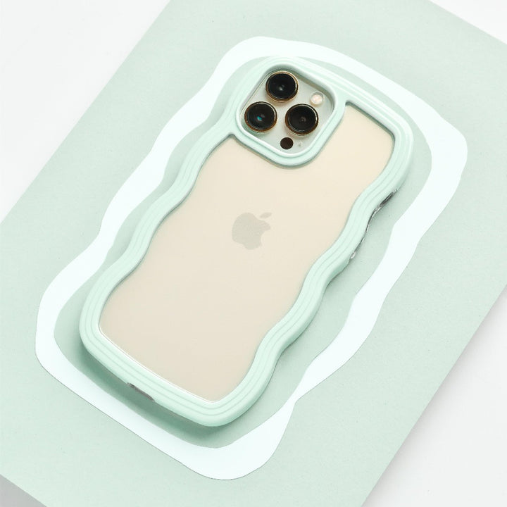 A beige iPhone 15 with three camera lenses on the back is placed on a mint green surface. The phone is encased in a Coconut Lane Curvy Phone Case - Mint, perfectly matching the surface color.