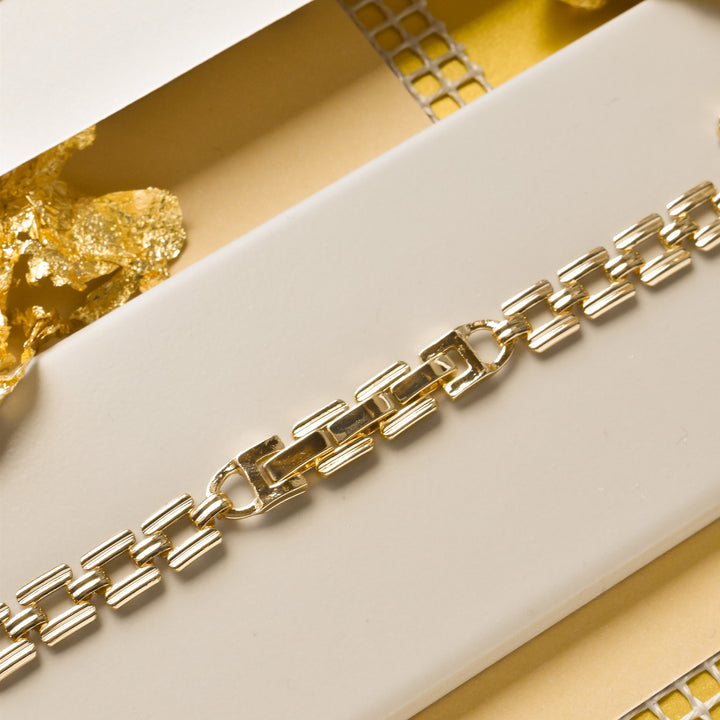 A close-up of a sleek Square Gold Bracelet Apple Watch Strap from Coconut Lane lies on a beige background. The strap features a modern, rectangular link design. Golden decorative elements are visible in the background, enhancing the luxurious appeal of the scene.