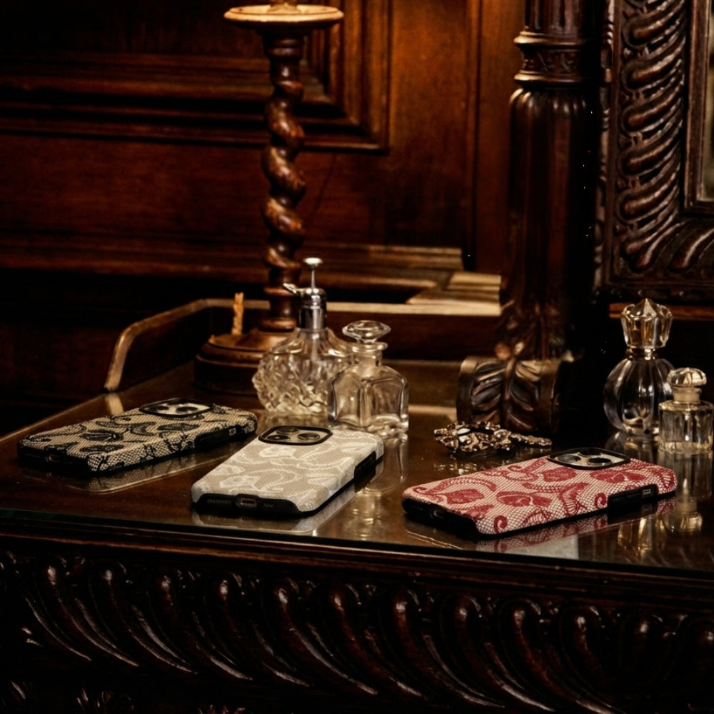 3 lace phone cases on a wooden table with decorative elements