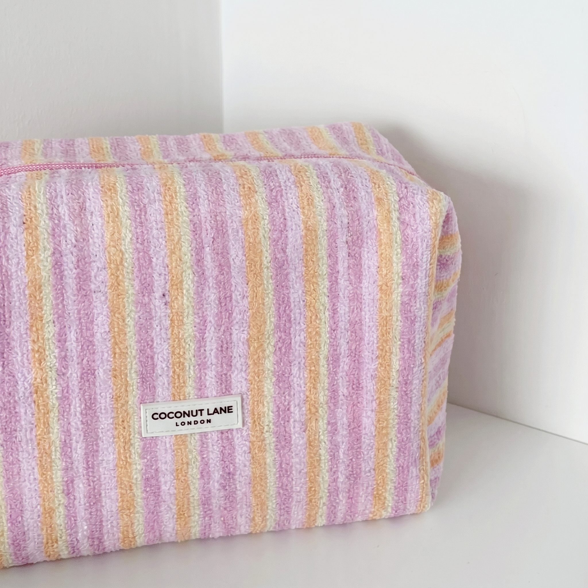 Pink, orange and yellow striped Makeup Bag in towel fabric with Coconut Lane logo.