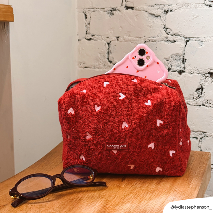 Mulberry Hearts Towel Makeup Bag on chair with Cute Hearts Phone Case inside of it next to a pair of glasses