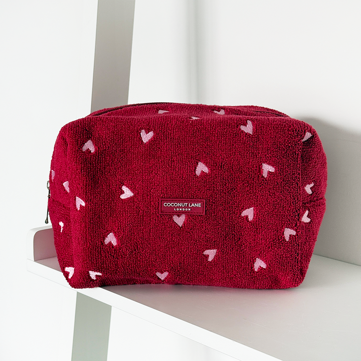 Red cosmetic bag with heart patterns on a white surface