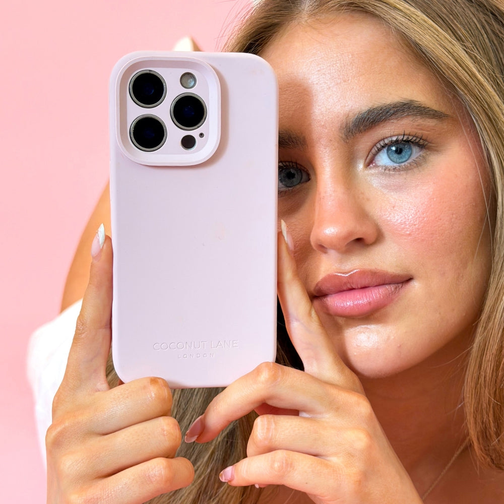 Woman holding a pastel pink phone case with a pink background
