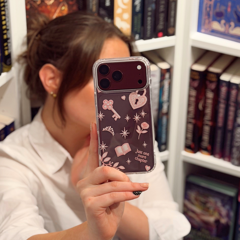 Woman in bookstore taking a selfie with a burgundy iphone. The iphone is in a Romance Girly Clear Phone Case showing intricate pink key, heart padlock, floral and star details with clear edges.
