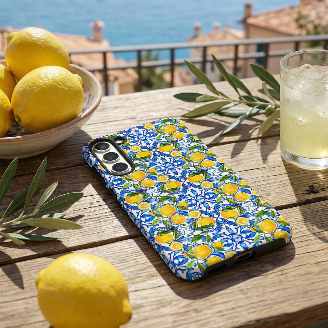 Samsung Tough Phone Case with Amalfi lemon pattern on a wooden table, alongside lemons, olive branches, and lemonade.