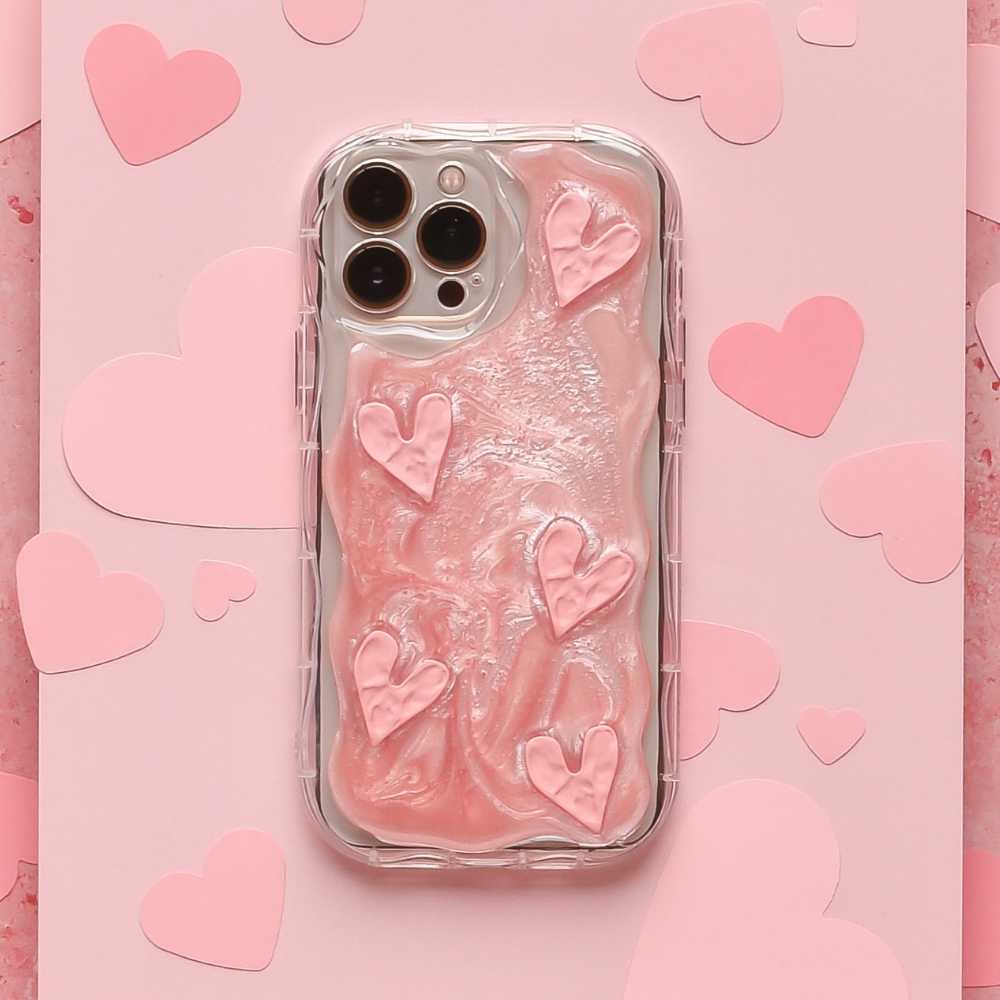 The Shimmer Pink Hearts Phone Case from Coconut Lane is a smartphone accessory that offers extra protection with its clear design, featuring raised, shimmer pink heart-shaped designs on a pink background. The background is adorned with cutout pink hearts, adding a romantic touch to the overall look.