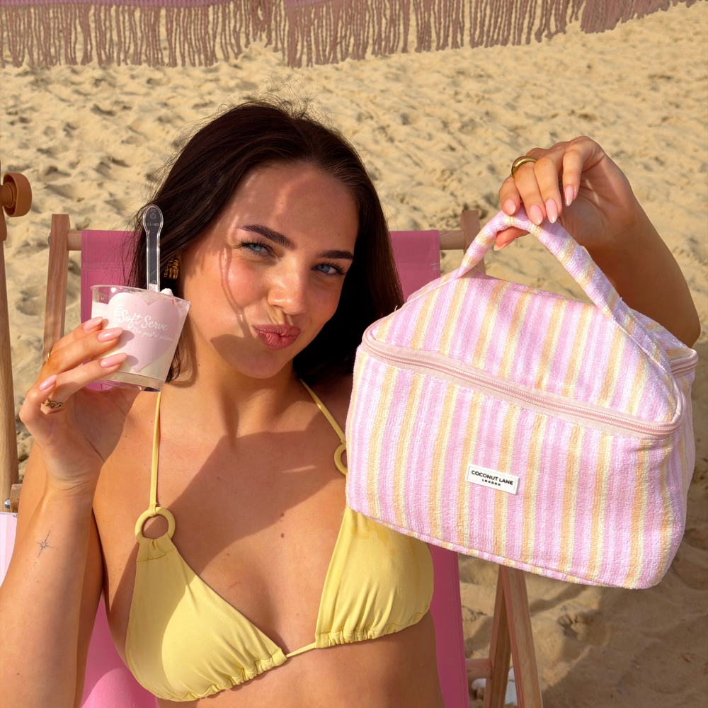 Girl posing with her vanity case pastel stripes in a towel material and her ice cream