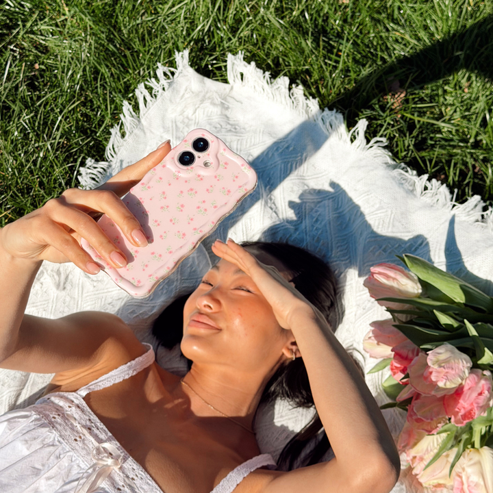 Girl at a picnic with flowers holding her Wavy Ditsy Floral Phone Case