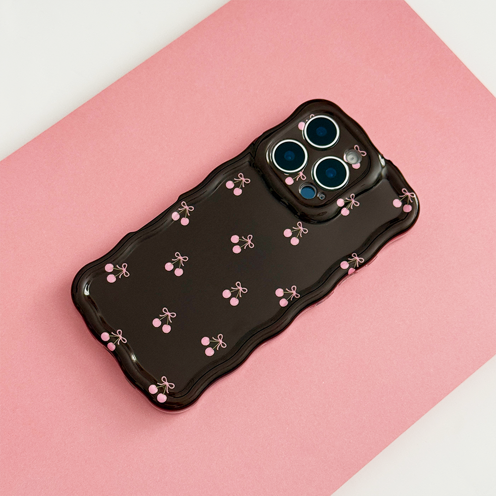 Wavy Phone Case featuring a glossy chocolate brown finish with delicate pink cherry and bow illustrations, wavy edges and triple camera cutouts, photographed on a pink background.