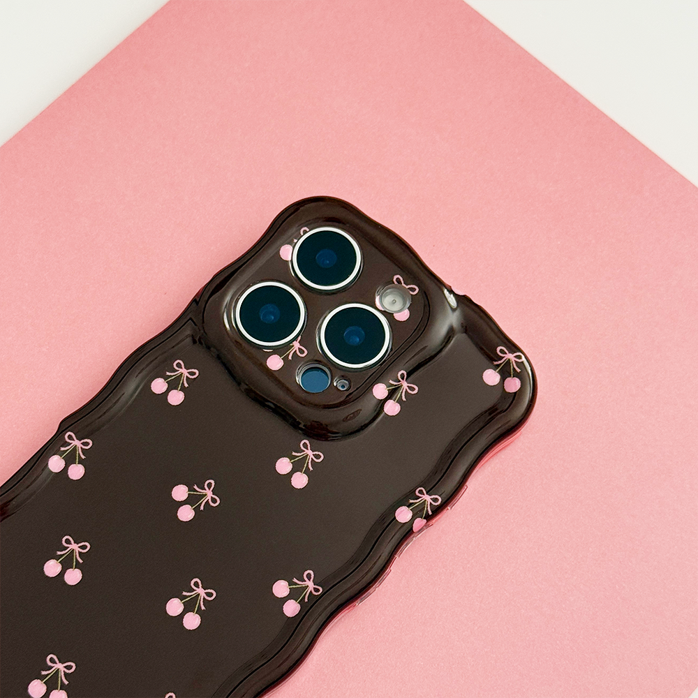Wavy Phone Case featuring a glossy chocolate brown finish with delicate pink cherry and bow illustrations, wavy edges and triple camera cutouts, photographed on a pink background.